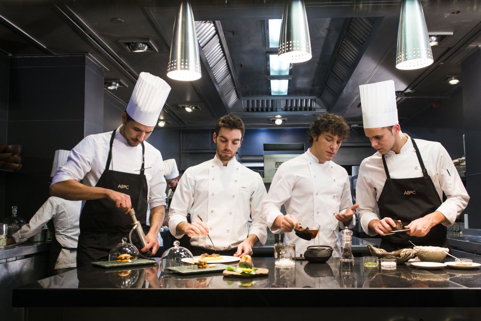GVL Four chefs in white uniforms and tall hats expertly prepare and plate gourmet dishes in a modern kitchen, embodying precision reminiscent of Japans culinary artistry. They work with various ingredients and utensils under bright overhead lights, ensuring each dish is a masterpiece.