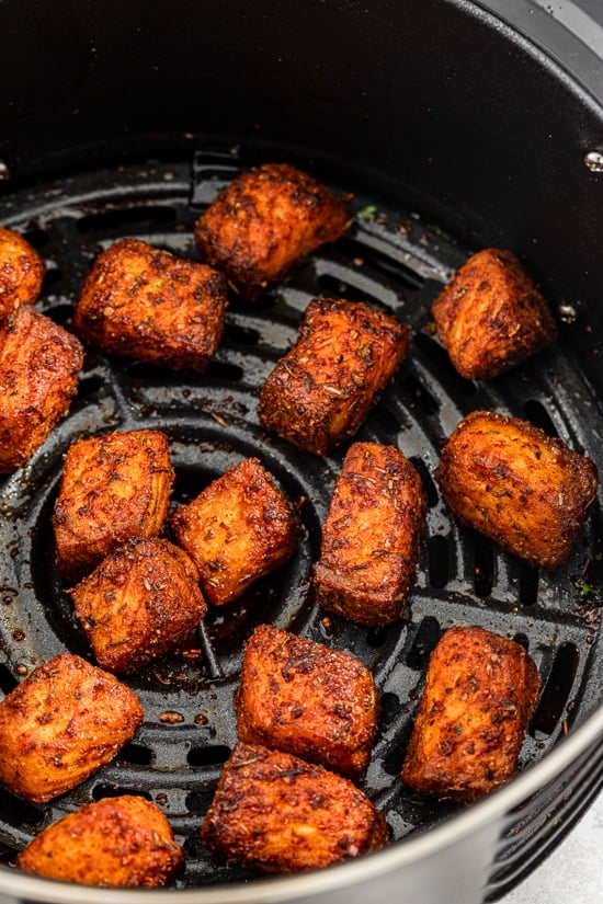 GVL Crispy, golden-brown Air Fryer Salmon bites are shown cooked in an air fryer basket, arranged in a single layer with visible spice coating—perfect for adding to your favorite Salmon Recipes.