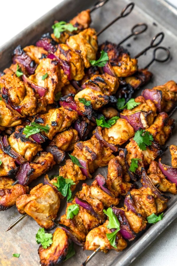 GVL Grilled Chicken Kebab skewers with marinated chicken and red onion, garnished with fresh cilantro and served on a metal tray.