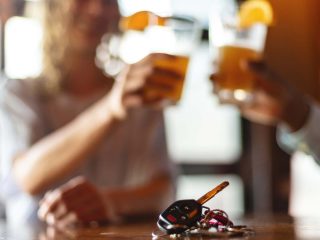 GVL Two people holding beer glasses and toasting in the background, with a car key and keychain placed on the table in sharp focus—highlighting concerns about liability insurance rates amid ongoing debates among SC lawmakers.