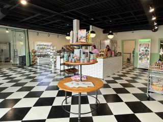 GVL A modern store with black-and-white checkered floors, round display tables with products, and shelves of goods in the background. This bright, spacious interior hints at a popular biscuit spot known for its Spartanburg flair and midtown expansion.