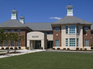 GVL A two-story brick and stone building with large windows, two cupolas on the roof, and a manicured green lawn in front, under a clear blue sky—showcasing the City Council’s commitment to a Mauldin budget with no tax increase.
