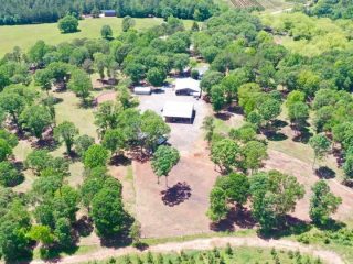 GVL Aerial view of Baugh Road Estate, a rural property in Liberty surrounded by green trees and fields, featuring a large central structure and smaller outbuildings—all offered at $1.4M.