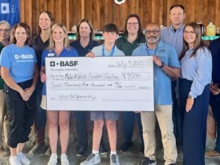 GVL A group of people stands together holding a large ceremonial check for $7,950 made out to Palmetto Animal Assisted Services, dated July 1, 2023, with BASF SC sites branding and Make-A-Wish logos visible on the check and shirts.